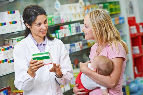A pharmacist talks with an adult with a baby.