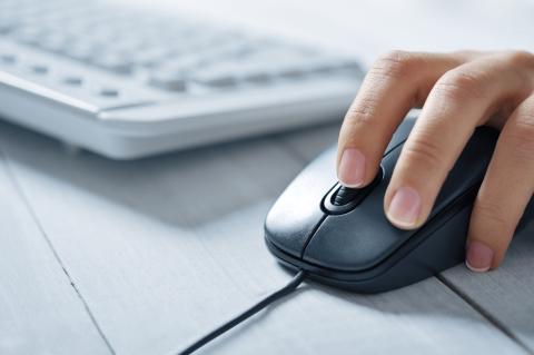 A hand on computer mouse with a keyboard