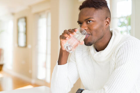Adult drinking a glass of water at home