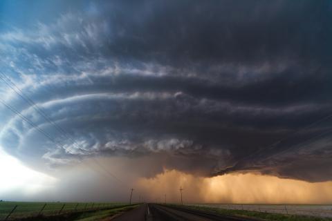 Huge funnel cloud developing into tornado over country field