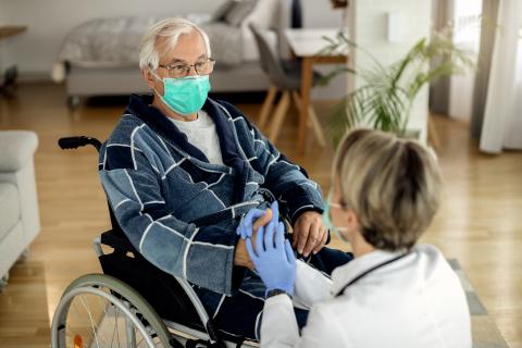 A medical professional hold the hand of an older adult in a wheelchair