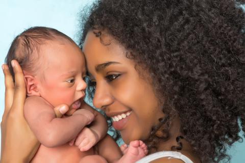 Smiling mother holds a newborn to her face