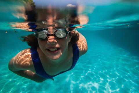 An underwater picture of a child swimming wearing goggles in a pool