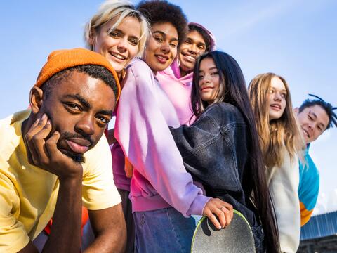 Seven smiling teens posing outside