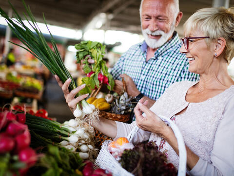 An older couple shopping for vegetables at the market