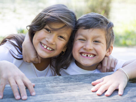 Two smiling kids with heads together