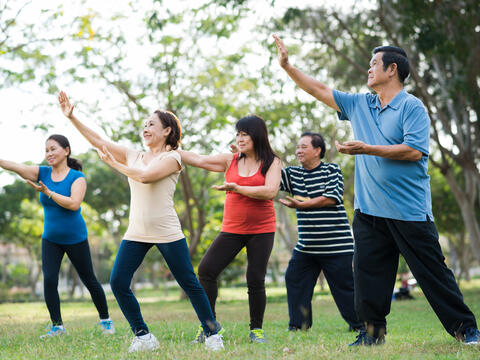 Five adults practicing tai chi outside.