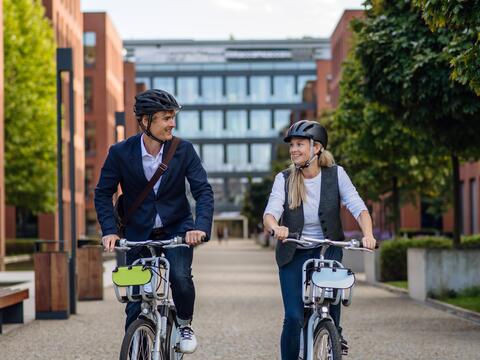 Two adults ride their bikes down a street