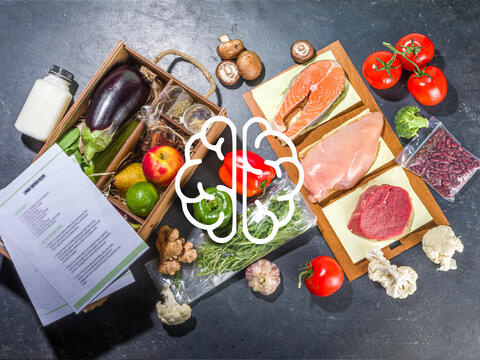 Healthy array of food displayed on a table with an outline of the human brain centered on image.