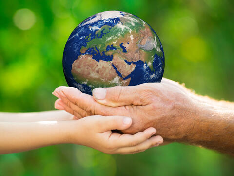 Earth being held in adult and child's hands