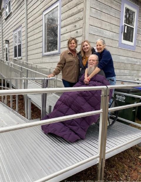 Two Accessibility Assessment Specialists/Modification Navigators with Options for Independent Living Stand Beside Ricki and William On Their New Ramp