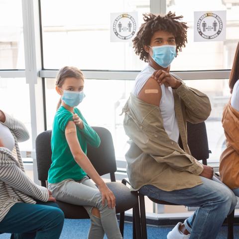 Four people showing their arm with band-aid after vaccination