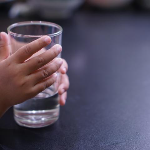 Child's hand holding a glass of water