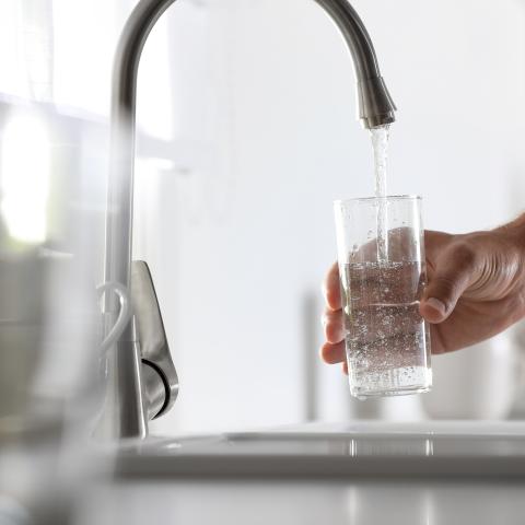 Glass of water being filled at a faucet