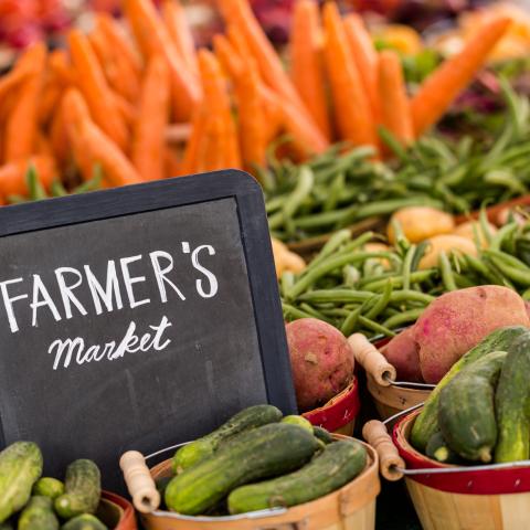 A chalkboard, "Farmer's Market", surrounds with baskets of vegetables.