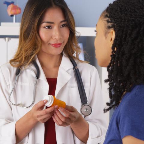 Doctor holding prescription bottle while talking to patient