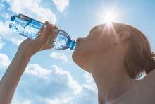 Young adult drinking bottled water in the sunshine