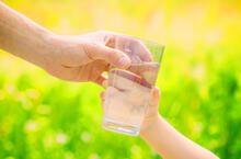 Adult hands glass of water to a child