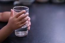 Child's hand holding a glass of water