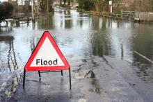A white triangle with red trim sign, flood, set on flooded road