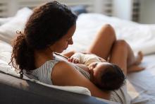 Mother on bed is breastfeeding baby