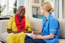 Nurse sitting with a patient and making notes at home.