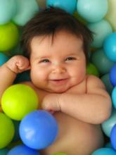 Smiling baby lying in a colorful ball pit.