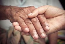 Elderly hand being held by a younger hand