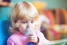 A child holds an oxygen mask to her face