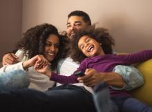 Family cuddled in the corner of a couch