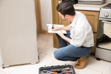 Worker writing up an estimate to repair an appliance