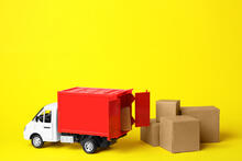 Toy truck with cargo area open showing boxes and boxes stacked on the ground next to truck