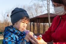 Adult holding an asthma inhaler for a young child