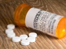 Oxycodone opioid on table next to open prescription bottle