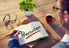 Adult at desk with open notebook and the word prevention