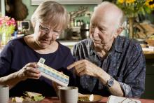 Elder couple sort their medications into a daily medicine organizer at home