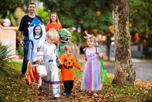 Parents with children in costumes trick or treating on Halloween