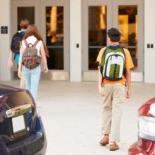 Kids walking into school wearing backpacks