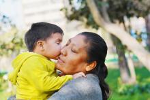 Close up of a toddler giving an adult a kiss