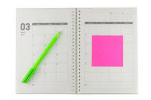 An open calendar book with a pen and a post it note.