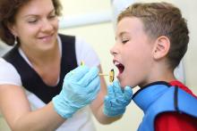 A dental hygienist putting a bite-blocker in a child's mouth.