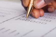 Close up of hand and pen completing a survey