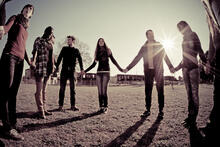 People form a large circle while holding hands outside
