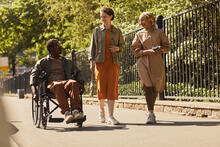 Three adults, one in a wheelchair, on a walking path