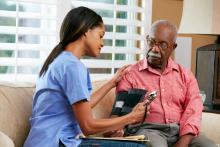 Nurse checking senior's blood pressure in home
