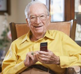 Smiling seated senior holding a mobile phone at home